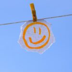 a smiley face sign hanging from a clothes line